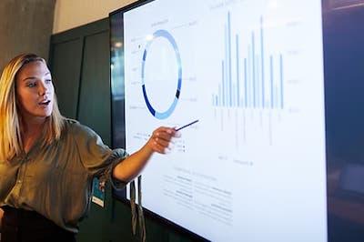 trainer pointing at a smart board with charts