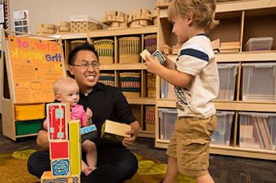 child care teacher with toddlers playing with blocks