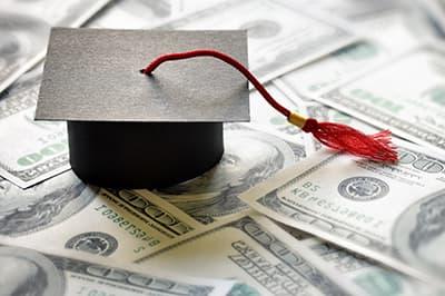 paper graduate cap on pile of cash