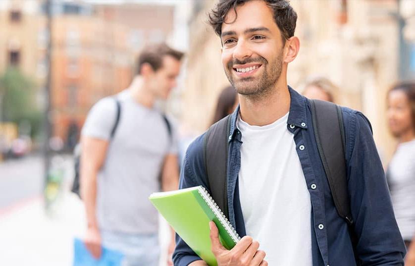 Student with notebook in city