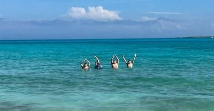 four people standing in the ocean