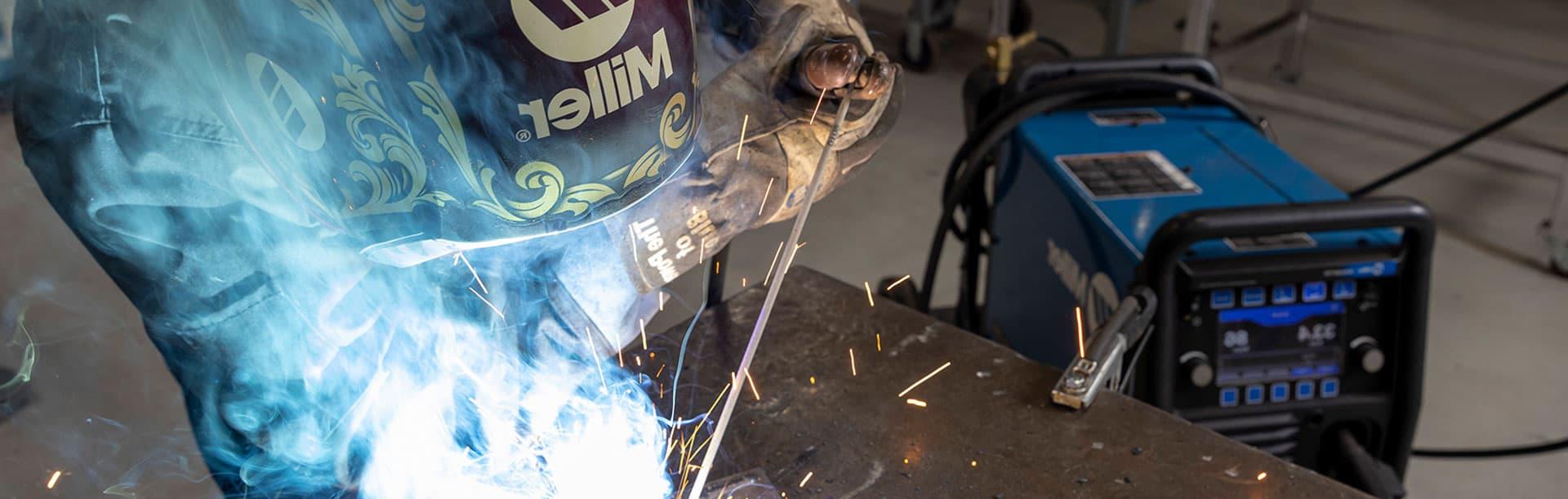 person in welding helmet welding with sparks flying